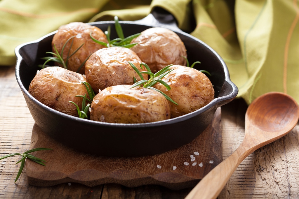 Golden baked potatoes with crispy skins and fresh rosemary in a cast-iron pan – Yummy Cooking Treats