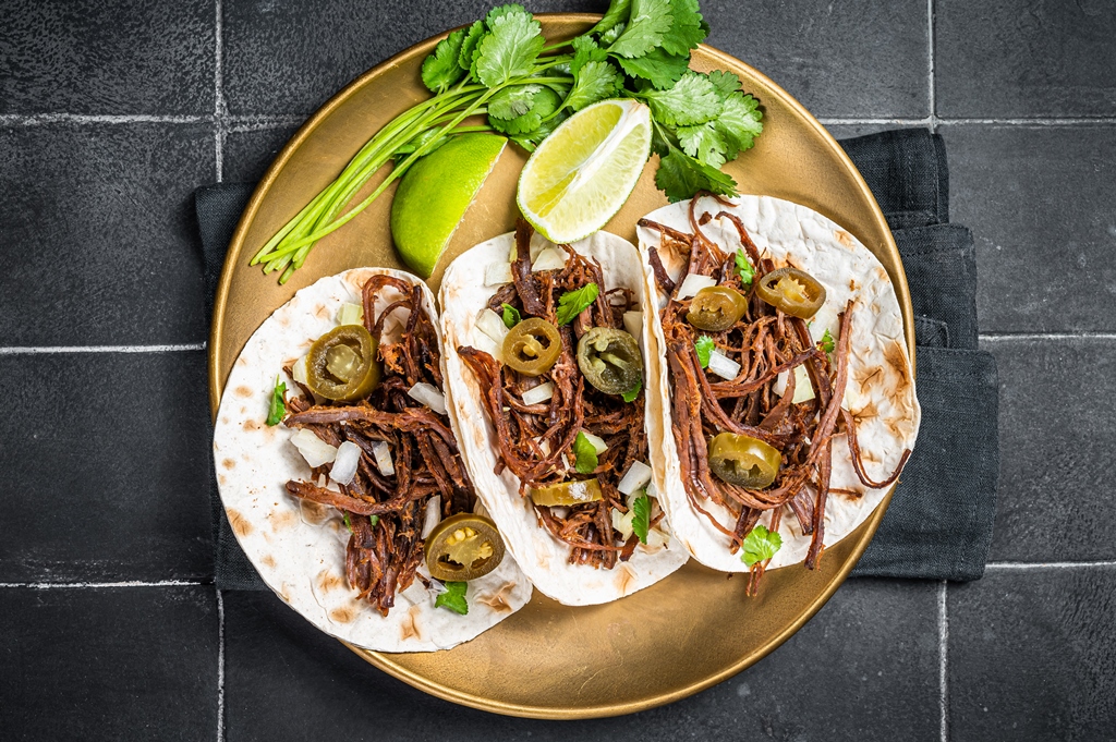 Three soft tacos filled with shredded barbacoa beef, onions, jalapeños, and cilantro on a gold plate with lime – Yummy Cooking Treats