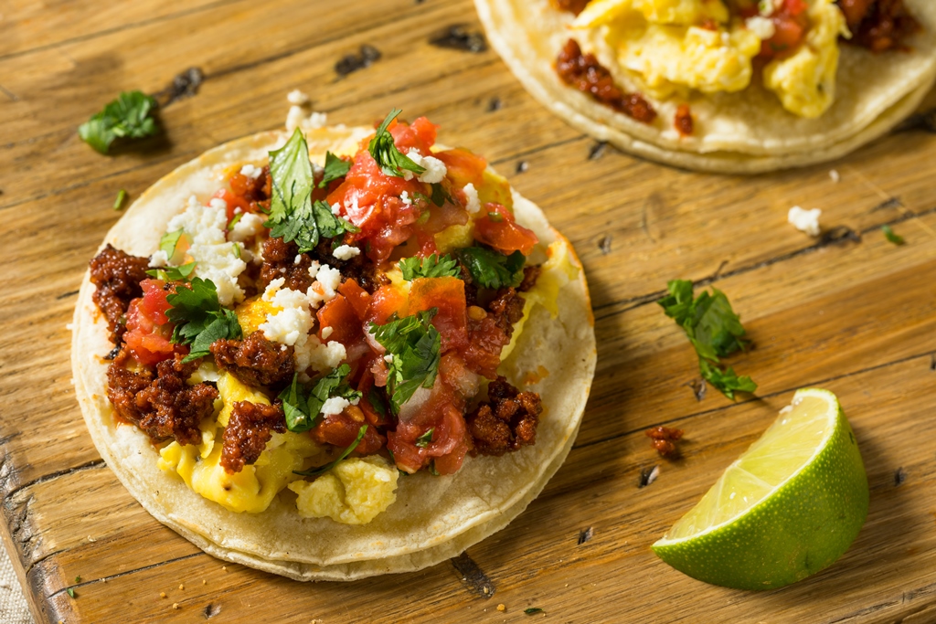 Soft tacos filled with scrambled eggs, chorizo, tomato salsa, crumbled cheese, and cilantro on a wooden surface – Yummy Cooking Treats