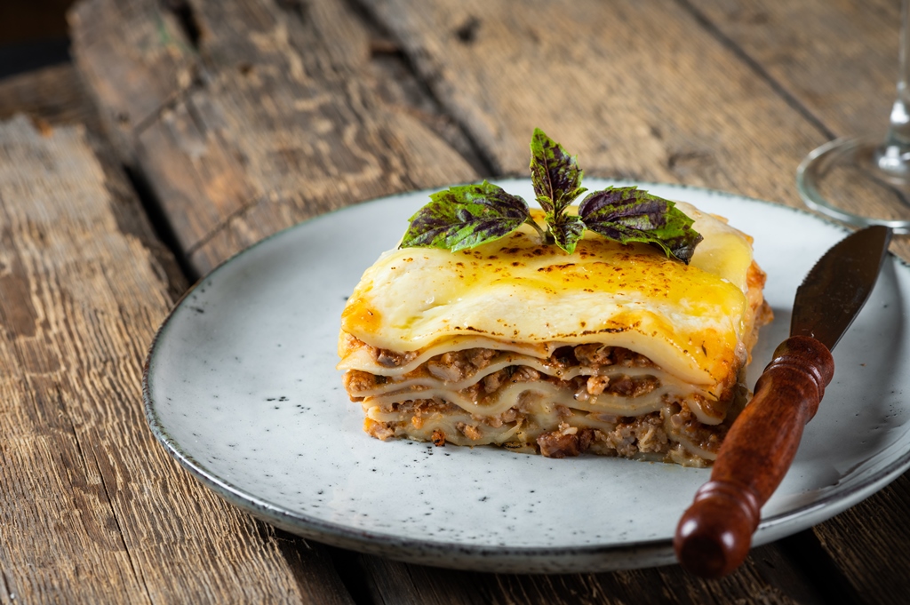 A slice of cheesy beef lasagna on a ceramic plate with basil garnish – a rustic Italian favorite from Yummy Cooking Treats