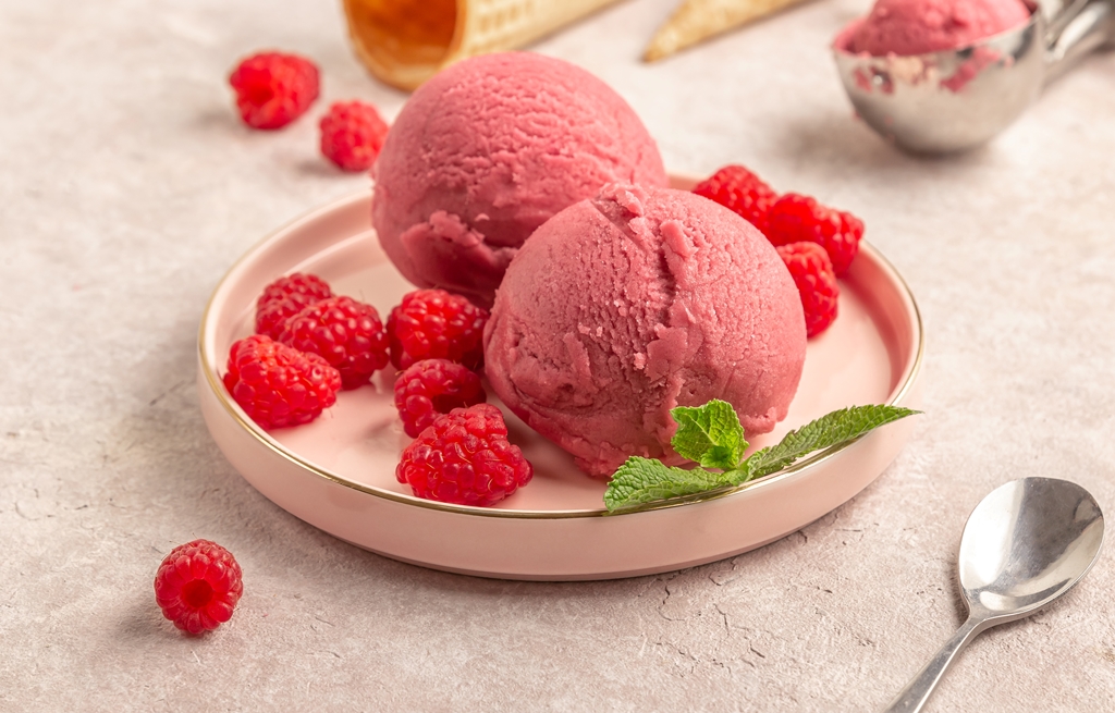 Two scoops of raspberry ice cream served on a pink plate with fresh raspberries and mint – Yummy Cooking Treats