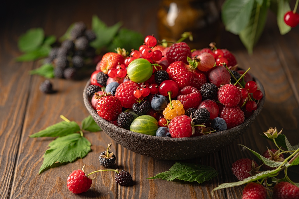 A rustic bowl filled with assorted fresh summer berries including strawberries, raspberries, blackberries, and currants – Yummy Cooking Treats