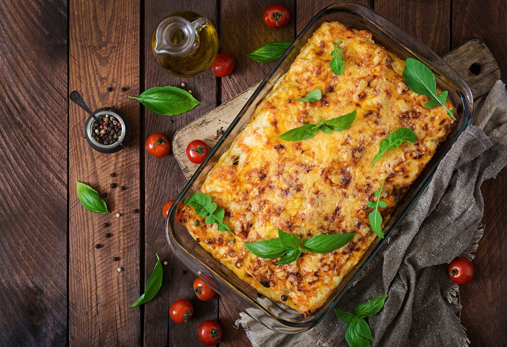 Golden chicken parmesan lasagna in a baking dish topped with fresh basil, ready to serve – styled by Yummy Cooking Treats