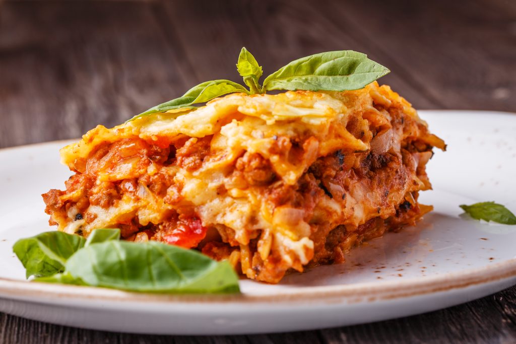 Layered chicken parmesan lasagna with melted cheese, marinara, and basil garnish on a plate – a homemade recipe by Yummy Cooking Treats