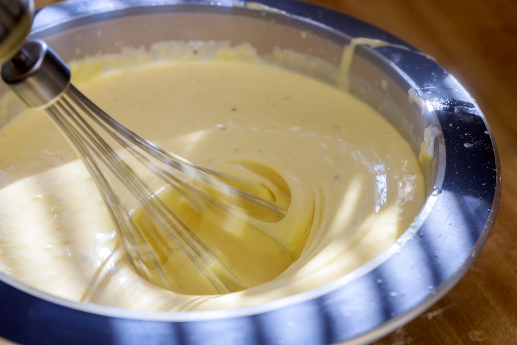 Whisk mixing creamy Swiss cheese sauce in a metal bowl – Yummy Cooking Treats homemade sauce in progress with smooth texture